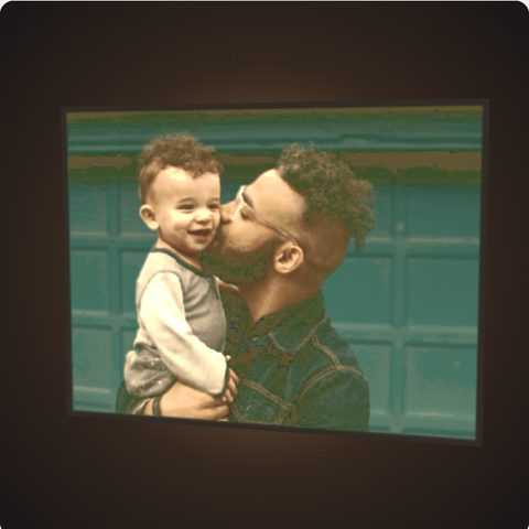 A full colour lithophane of a dad kissing his laughing toddler, glowing with light behind it